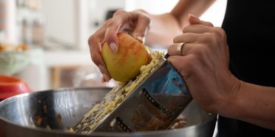 Žena na struhadle strouhá jablko.