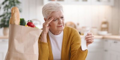 Seniorka se dívá ustaraně na účet z obchodu