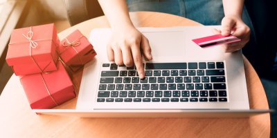 Žena sedí s notebookem a drží v ruce kartu