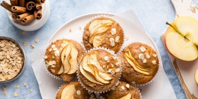 Jablečné muffiny, v pozadí jablka, skořice a ovesné vločky