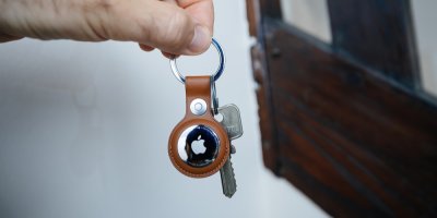 Ruka držící kožený přívěsek na klíče obsahující lokátor Apple Airtag