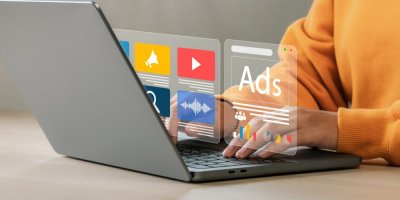 Žena je na notebooku, před ní je grafika reklamy