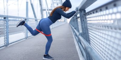 Žena se rozcvičuje na mostě v čepici a rukavicích