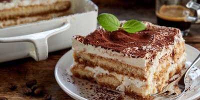 Tiramisu na talíři, v pozadí káva a tiramisu v zapékací míse