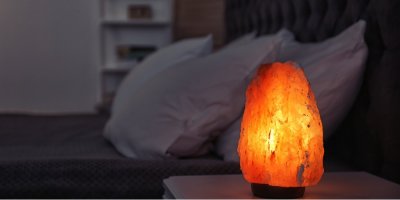 Rozsvícená solná lampa na nočním stolku vedle postele