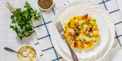 Talíř se zapečeným květákem, slaninou a sýrem, vedle bylinky a dip