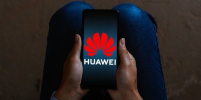 Telefon s logem Huawei drží ruce v klíně