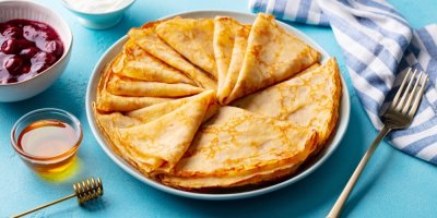 Palačinky na talíři, vedle med a ovoce