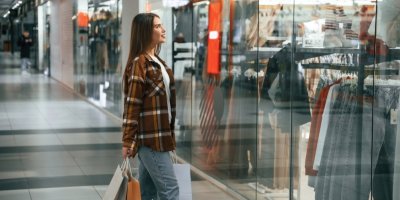 Žena v obchodním centru pozoruje výlohu s oblečením
