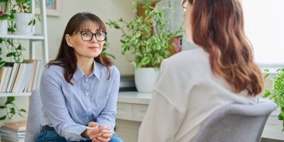 Žena s propiskou poslouchá jinou ženu.