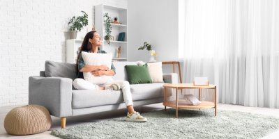 Žena sedí na gauči s polštářem v ruce