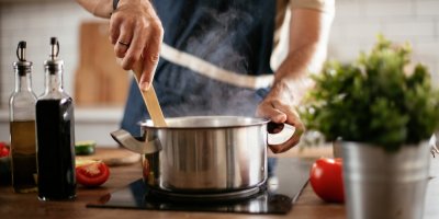 Kuchař míchá v hrnci vařečkou