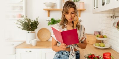 Žena kouká zamyšleně do kuchařky