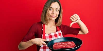 Žena ukazuje palec dolů nad pánví s masem
