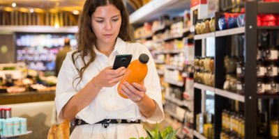 Žena si v supermarketu skenuje čárový kód džusu