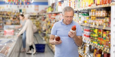 Starší muž v supermarketu, prohlíží si zboží