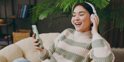 Žena v křesle poslouchá hudbu z bezdrátových sluchátek.