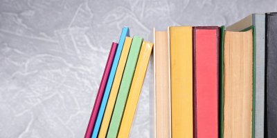 Srovnané barvené knihy o různých tloušťkách na poličce