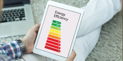 Člověk drží v ruce tablet s obrázek energetických štítků