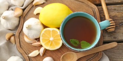Česnekový čaj na prkénku se snítkou máty, vedle česnek a citron