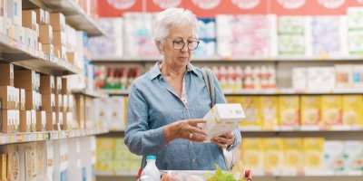 Seniorka si čte text na krabici v obchodě