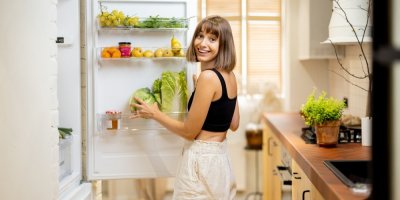 Žena se usmívá a stojí u otevřené lednice