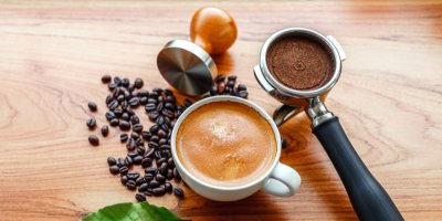 Káva v hrníčku, vedle v páce do kávovaru