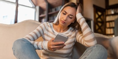 Žena se mračí a kouká do telefonu