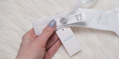 Ženská ruka drží bílé dámské prádlo s cedulkou Primark.