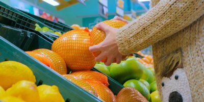 Člověk si v obchodě vybírá pomelo zabalené do fólie