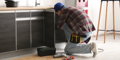 Muž opravuje něco pod dřezem