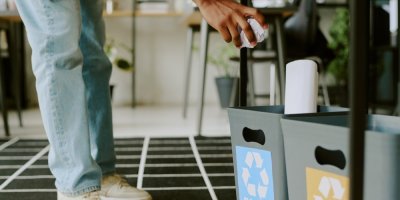 Muž hází papír do koše na tříděný odpad