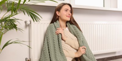 Žena v dece sedí u radiátoru