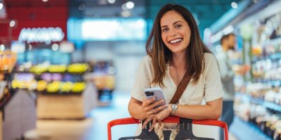 Žena se opírá o nákupní vozík a usmívá se