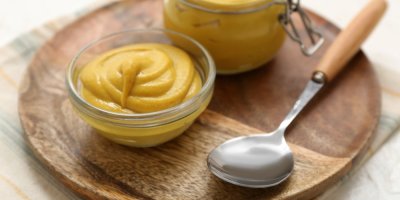 Hořčice ve skleněné v misce, vedle lžíce