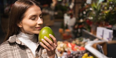 Žena čichá k mangu v supermarketu