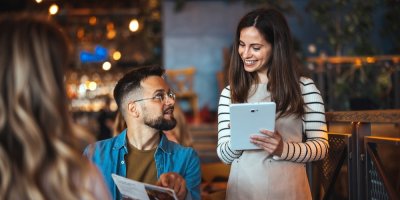 Muž si v restauraci objednává u servírky z jídelního lístku.