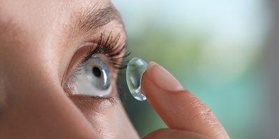 Žena si dává do oka kontaktní čočku