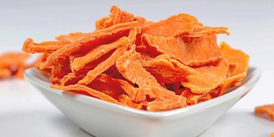 Keramická miska plná oranžových plátků sušené dýně