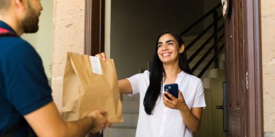Žena přijímá tašku s jídlem od kurýra
