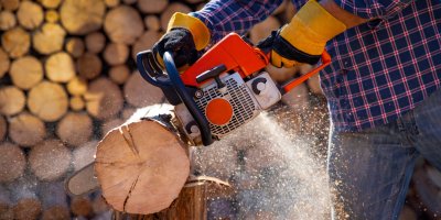 Muž řeže kládu motorovou pilou