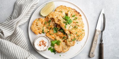 Dva plátky květákového steaku na talíři s dipem a limetkou