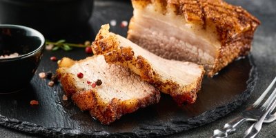 Pečený bůček a dva plátky na černém talíři