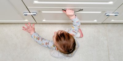 Batole se snaží otevřít skříňku zajištěnou dětskou pojistkou.