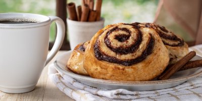 Skořicové rolky, vedle hrnek s kávou