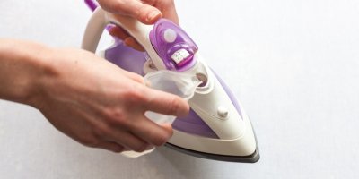 Ruka nalévá vodu do žehličky