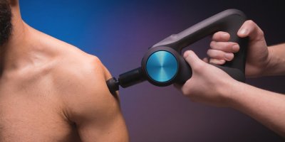 Masér masíruje přístrojem rameno muže