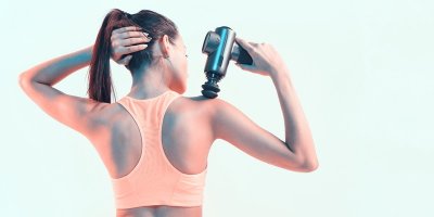 Žena si masíruje záda přístrojem