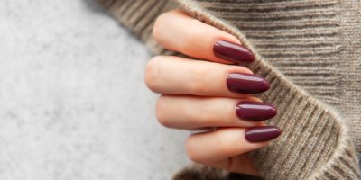 Ruka s nalakovanými nehty v barvě burgundy