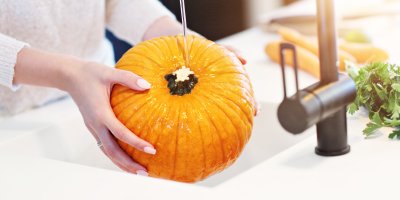 Žena omývá dýni ve dřezu